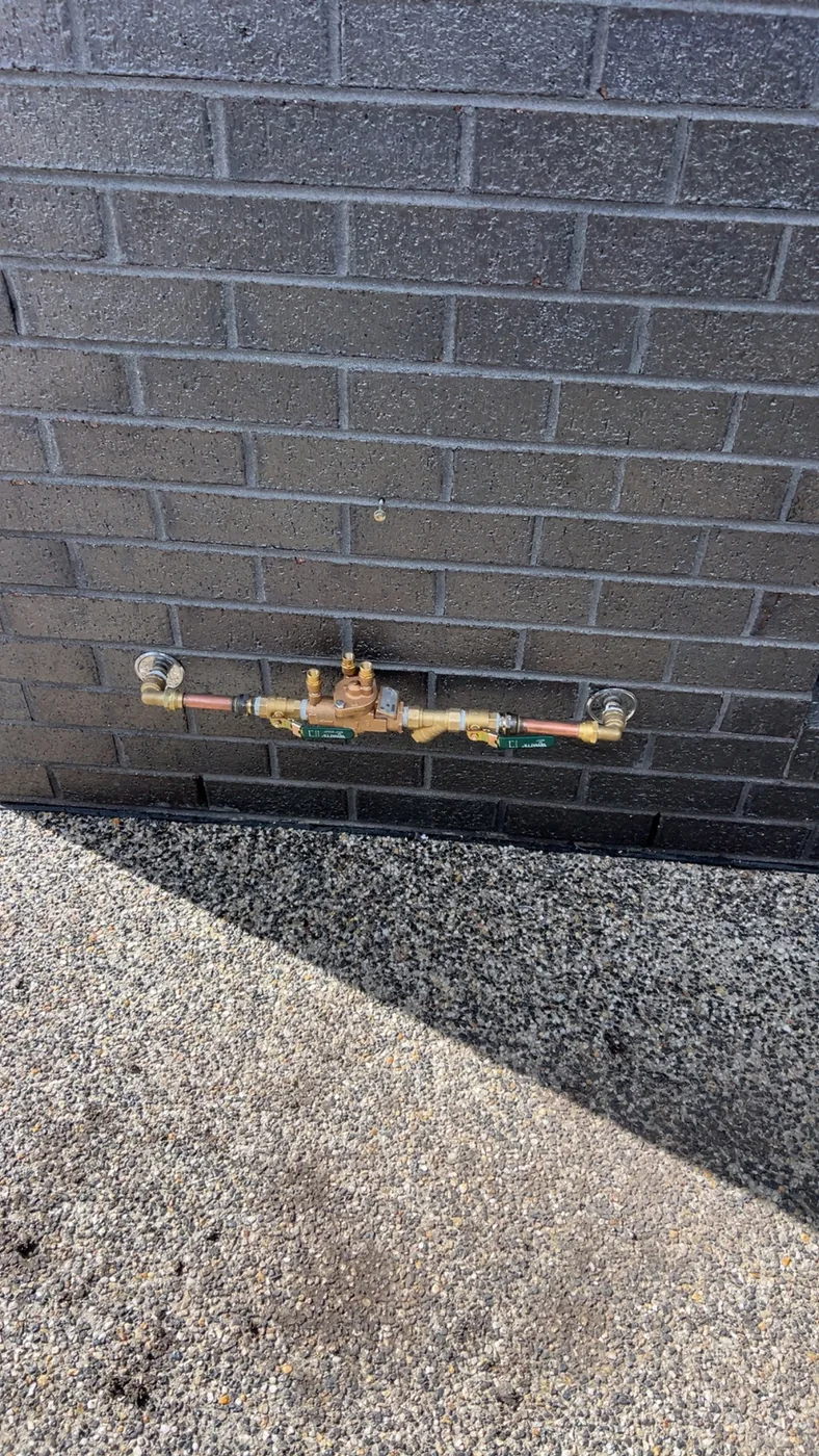 Copper pipework and valves mounted neatly against a brick wall