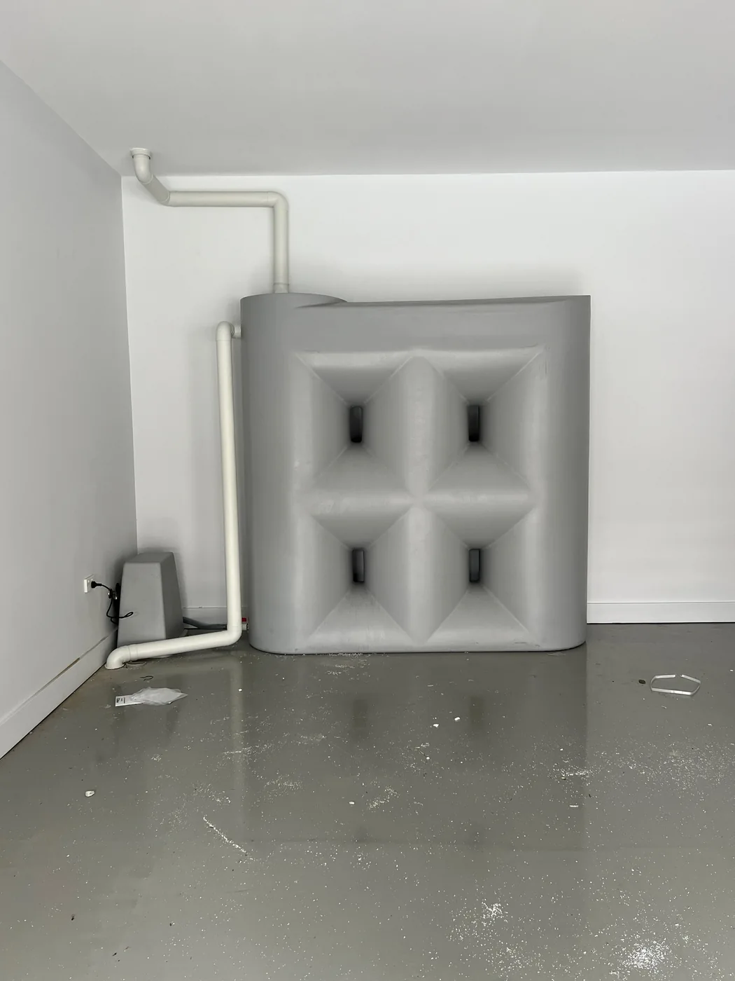 Water storage tank with connected white pipework in a garage